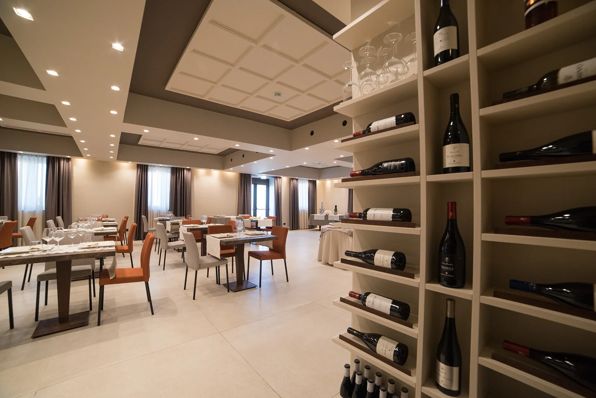 Sala interna del ristorante con tavoli apparecchiati, sedute moderne e illuminazione calda in ambiente elegante