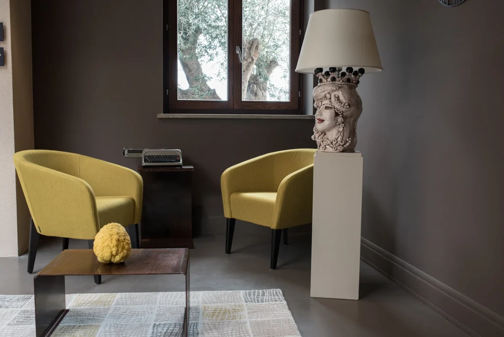 Area comune dell’hotel con due poltrone moderne, tavolino basso e decorazioni in stile contemporaneo vicino a una finestra.