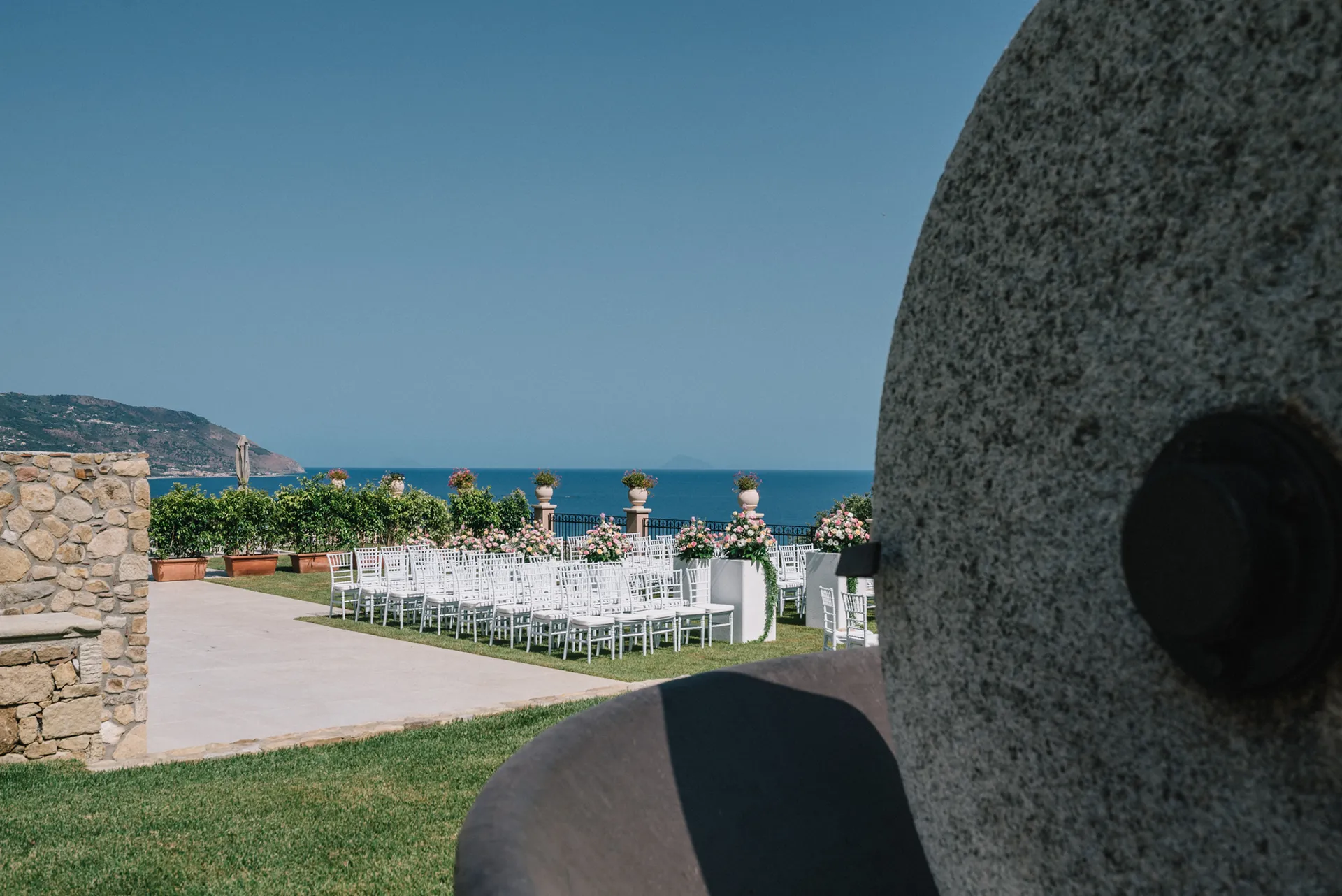 Terrazza panoramica dell’Hotel Terre di Eolo a Patti allestita per una cerimonia all’aperto, con sedie bianche, composizioni floreali e vista sul mare e sulle colline circostanti